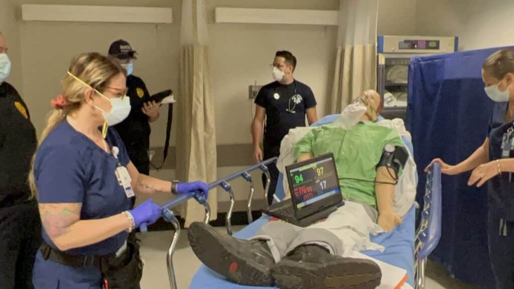 hospital workers gather around a patient dummy